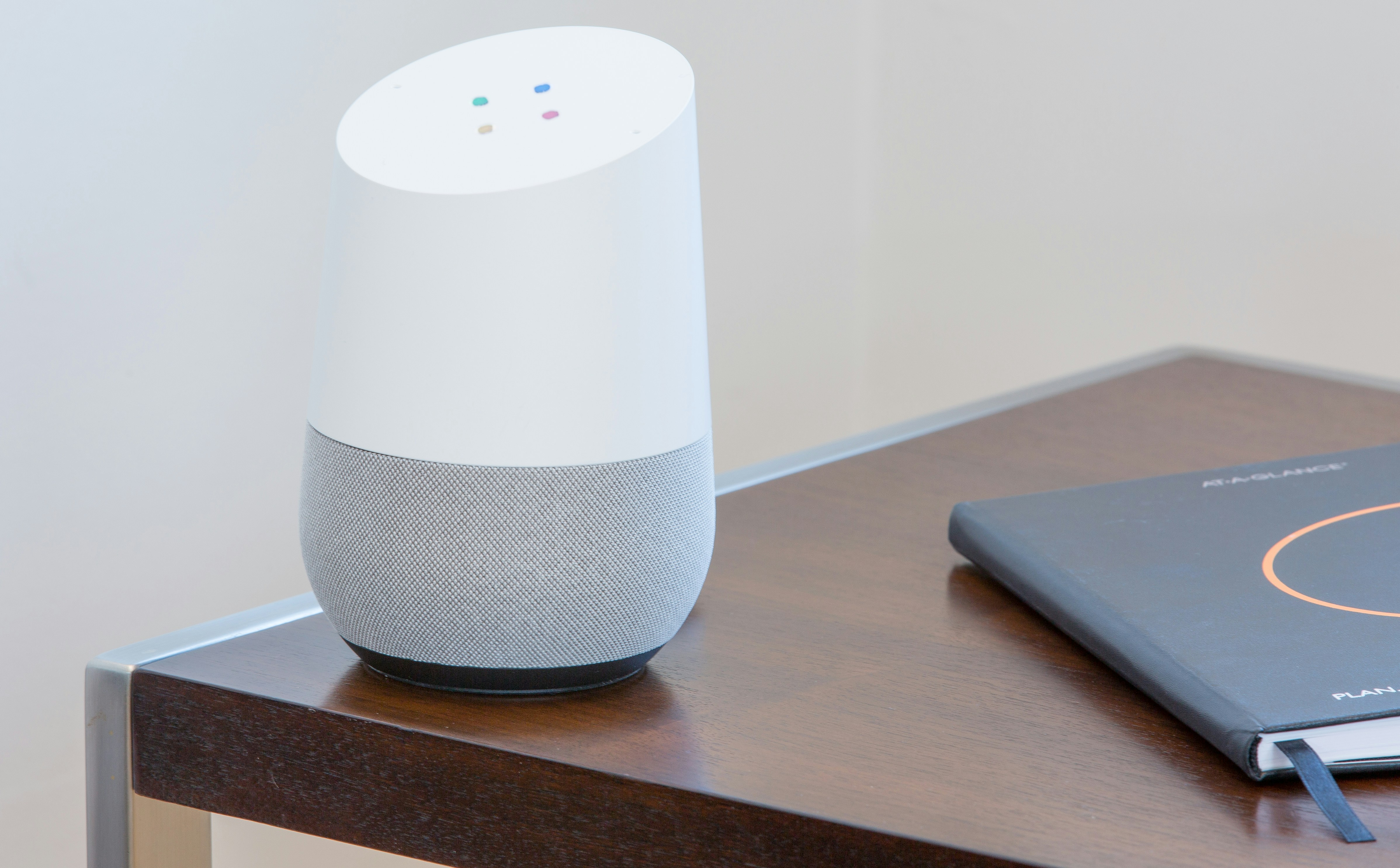 Google Home speaker on table with notebook