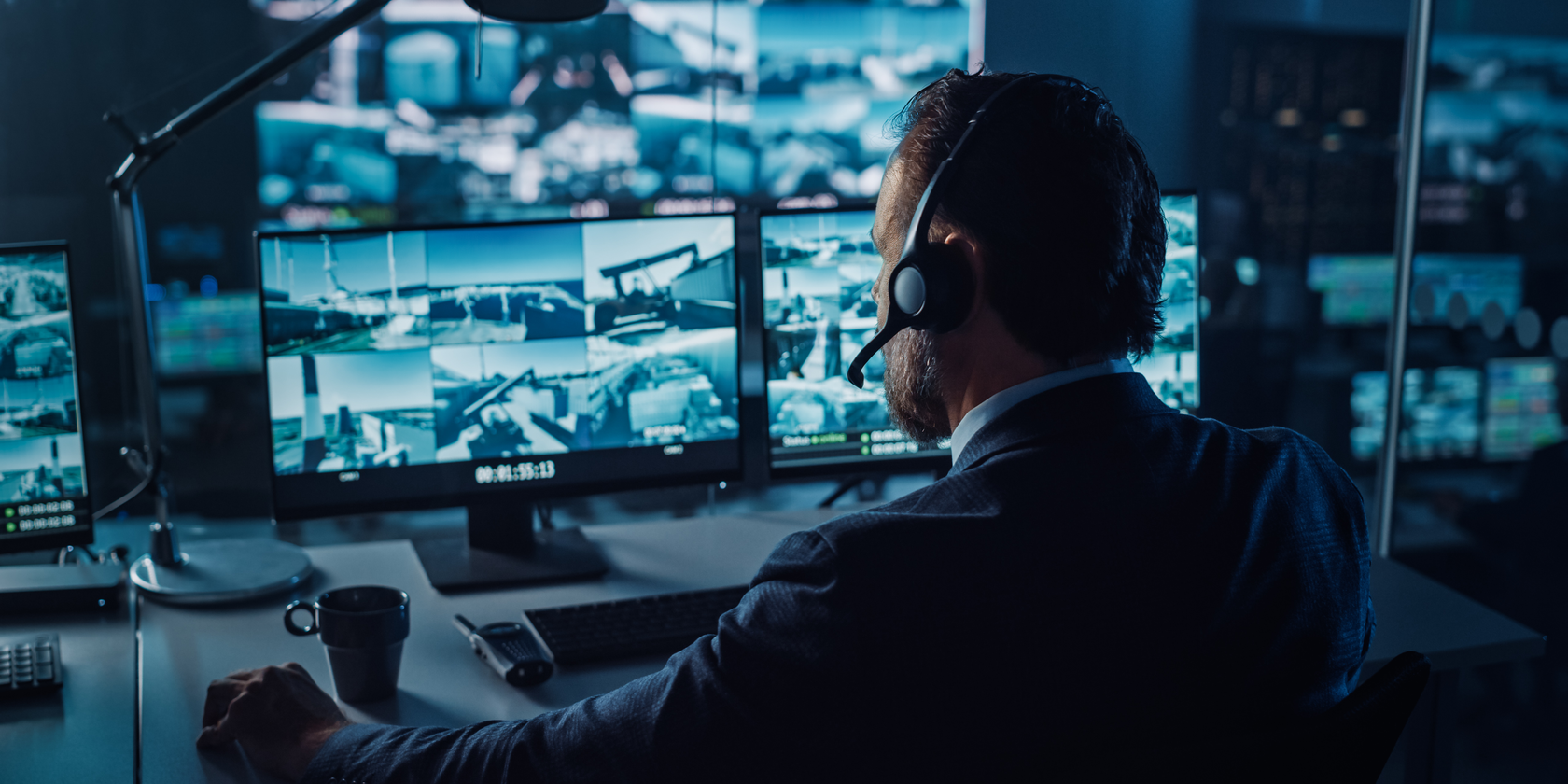 Man in front of monitors watching security camera footage